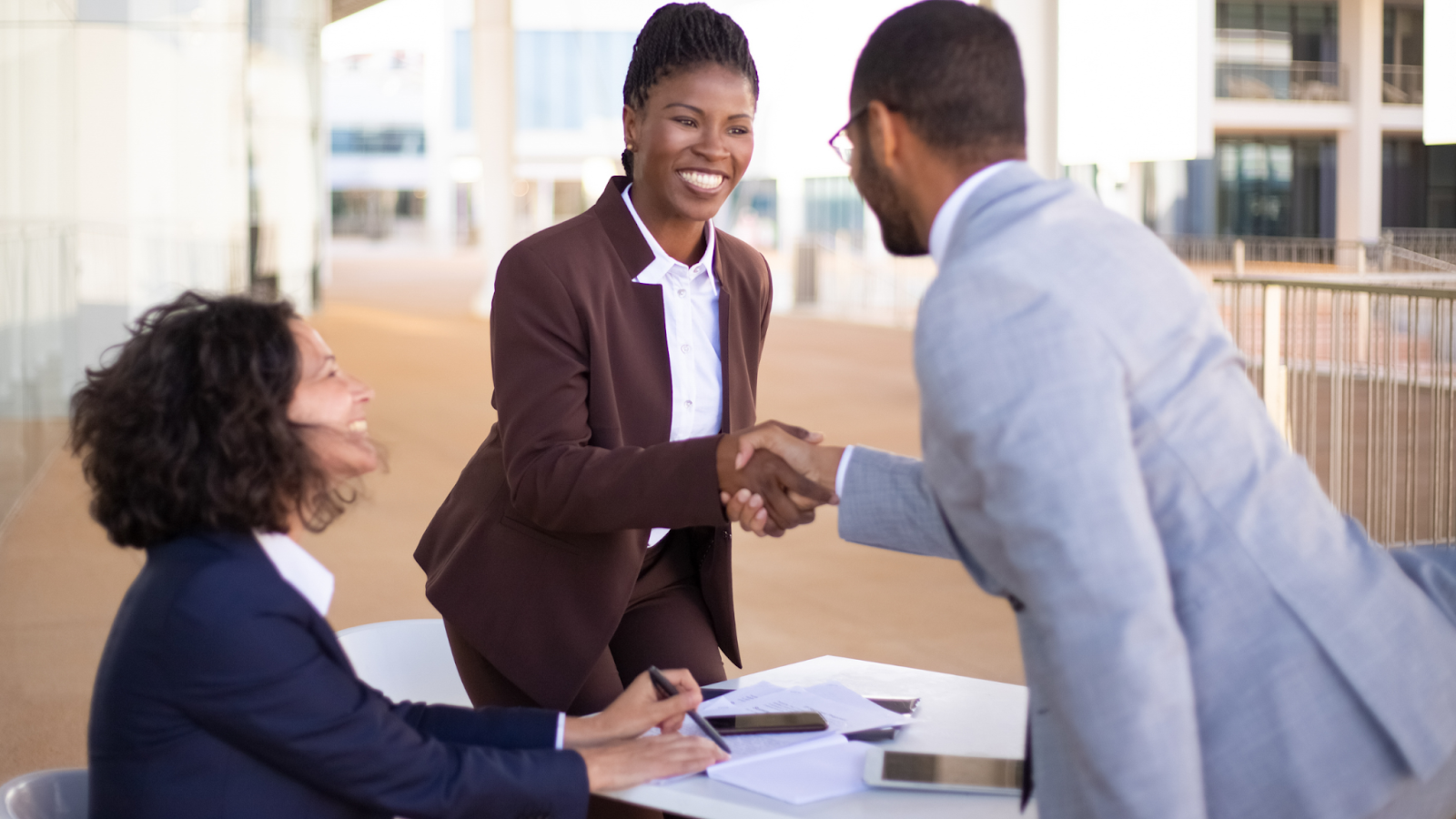 An employer congratulates a new hire they found thanks to a stable job market.