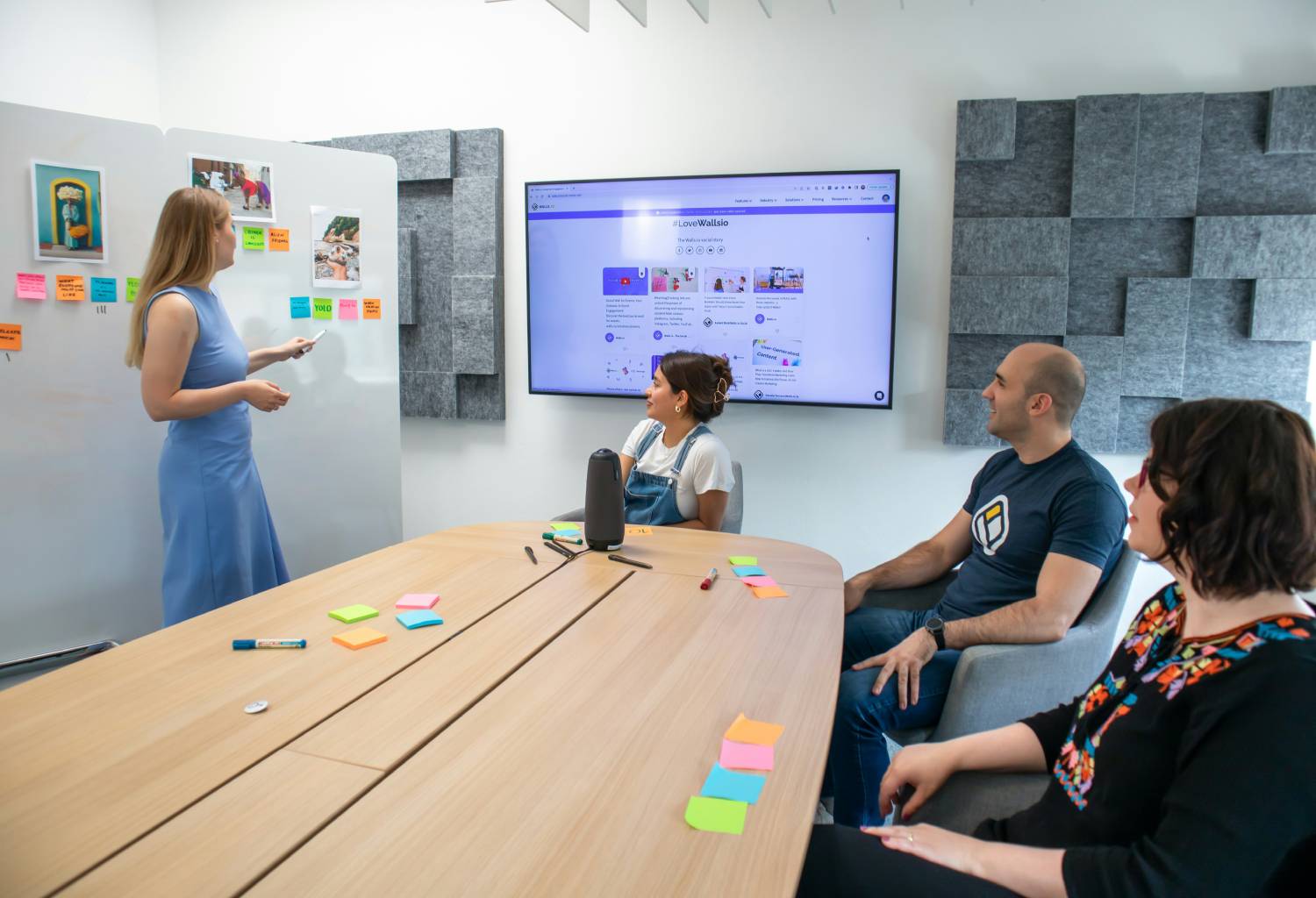 Woman leading a creative brainstorming session in a modern meeting room, pointing at a whiteboard 