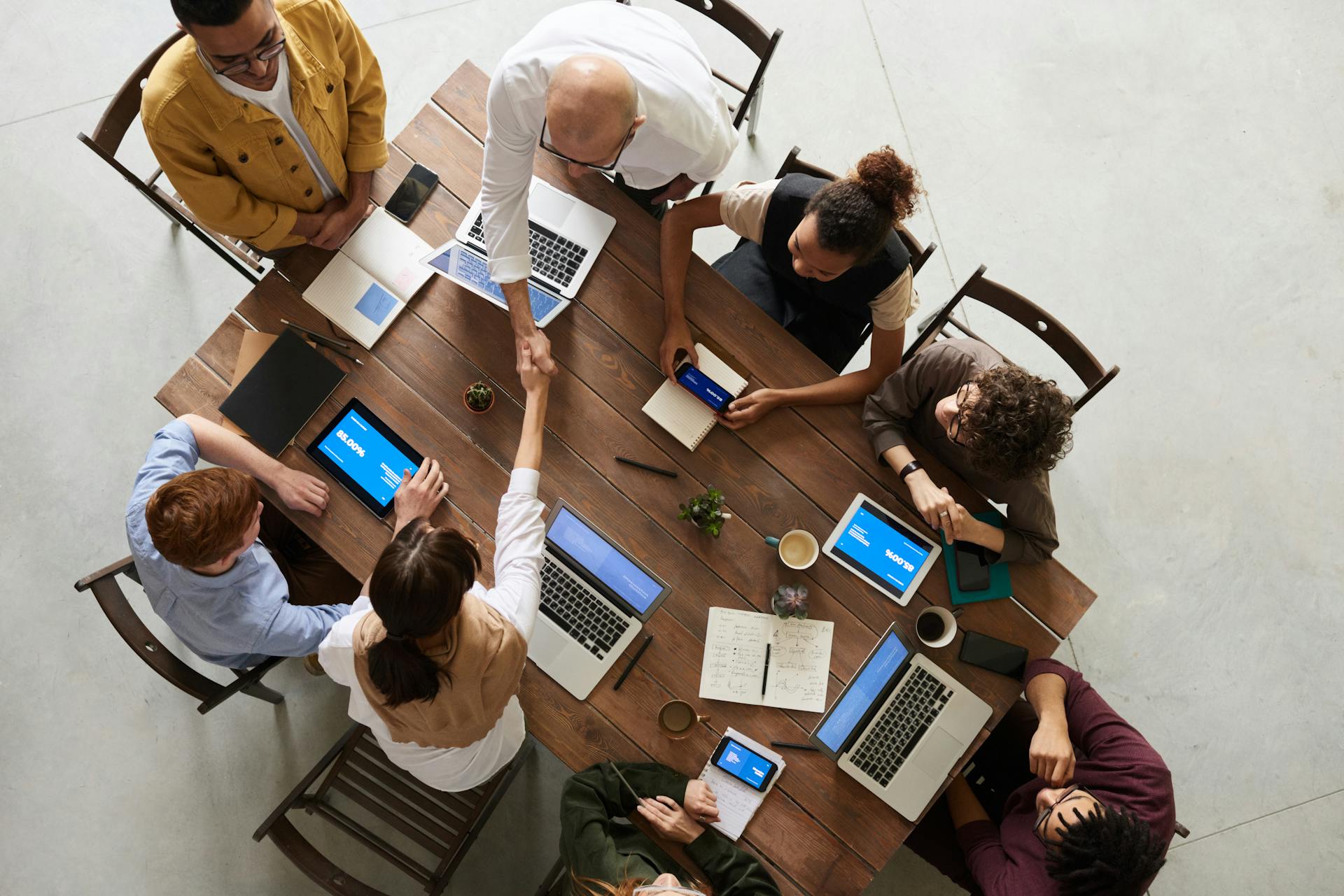Top-down view of diverse professionals collaborating around a table, symbolizing strategic networking and peer insight.