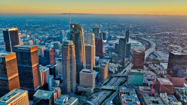 Aerial view of downtown Los Angeles at sunset, with high-rise buildings.
